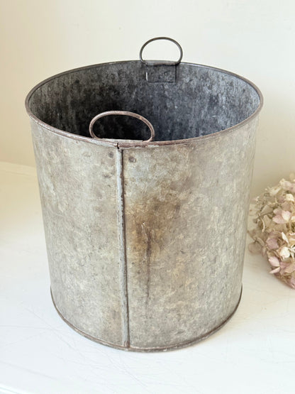 Vintage galvanised metal bin with handles, photographed on a white surface.