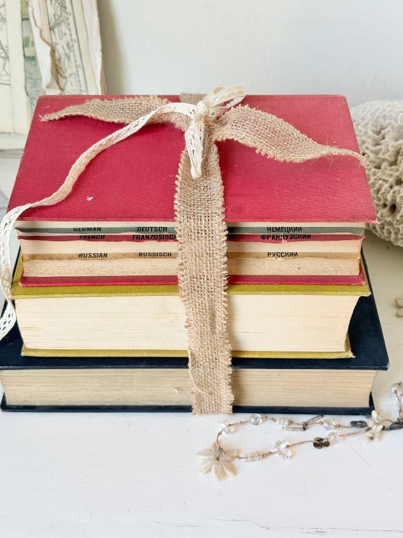 Vintage decorative book bundle in blue yellow and red with aged hardback covers tied with natural ribbon for bookshelf styling