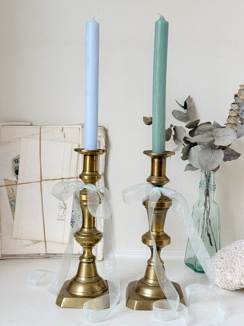 Pair of tall antique brass candlesticks with knopped columns and octagonal stepped bases holding blue and green tapers