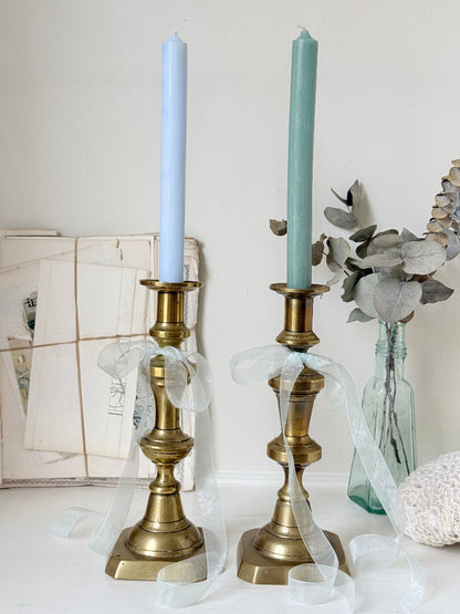 Pair of tall antique brass candlesticks with knopped columns and octagonal stepped bases holding blue and green tapers