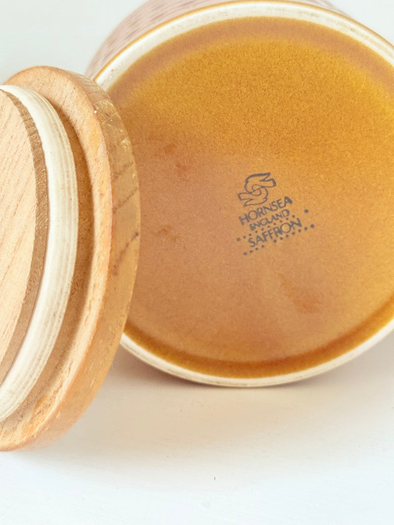 Vintage Hornsea kitchen canister in Saffron yellow with wooden lid photographed on a white surface.