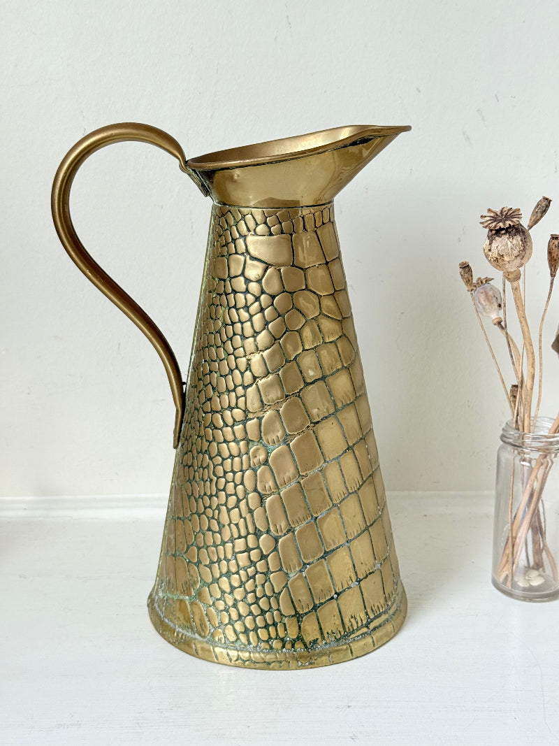 Vintage brass jug with alligator patterned surface, photographed against a white background.