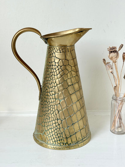 Vintage brass jug with alligator patterned surface, photographed against a white background.