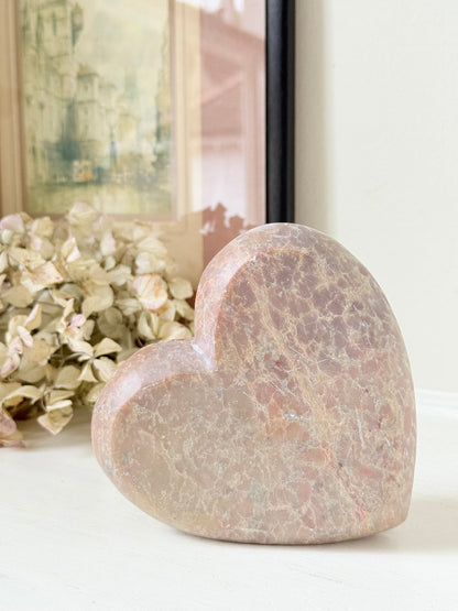 vintage pink stone heart with engraved roses and flat base on white surface