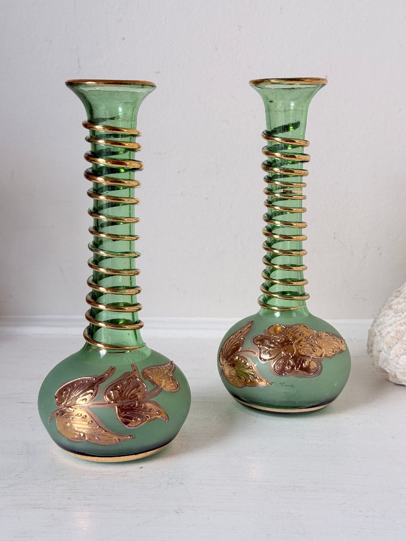 Pair of vintage green glass candlesticks with gold detail and spiral stems styled with blue taper candles on white surface