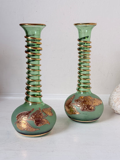 Pair of vintage green glass candlesticks with gold detail and spiral stems styled with blue taper candles on white surface