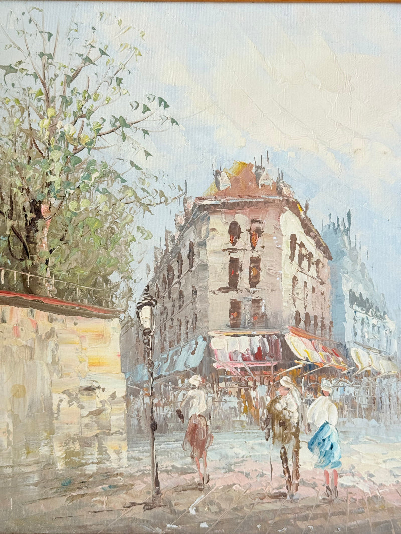 Vintage oil painting of European street scene with buildings and awnings in wooden frame photographed on a white surface

