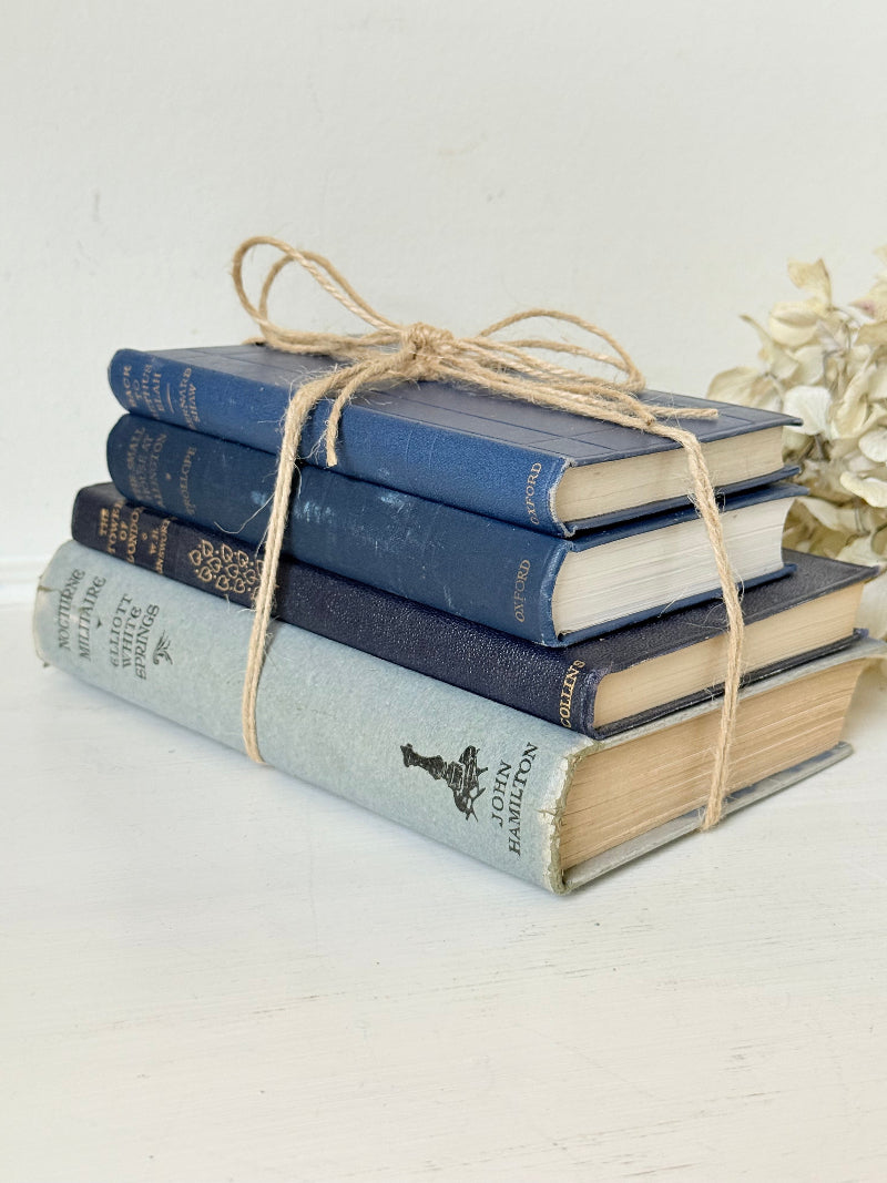 Vintage decorative book bundle in navy, grey, and cream tied with twine, photographed on a white surface