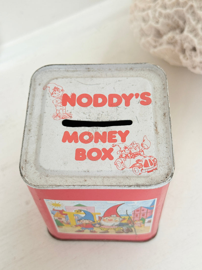 Vintage Noddy money box tin in red with illustrated panels, photographed on a white surface