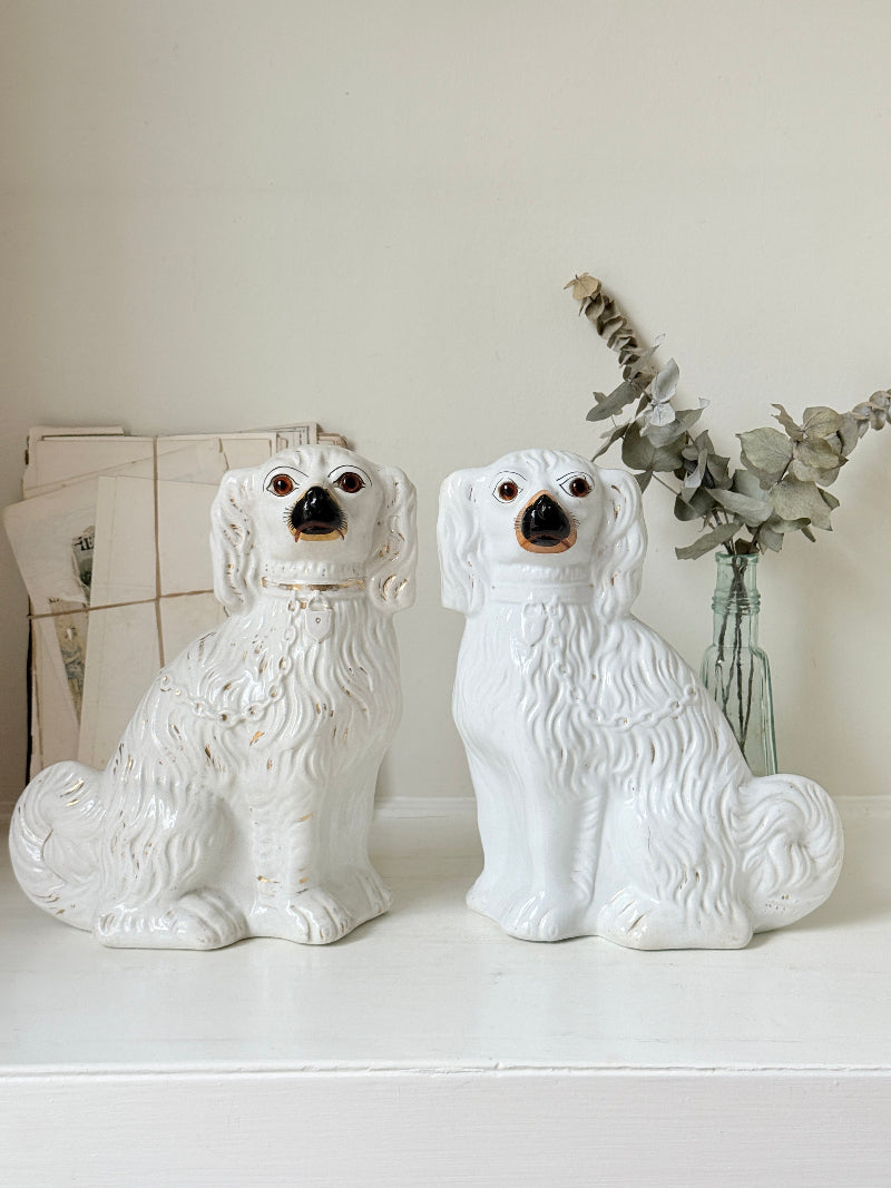 Near pair of antique white Staffordshire spaniel mantel dogs with glass eyes and worn gilt collars