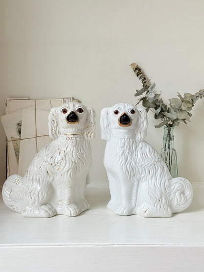 Near pair of antique white Staffordshire spaniel mantel dogs with glass eyes and worn gilt collars