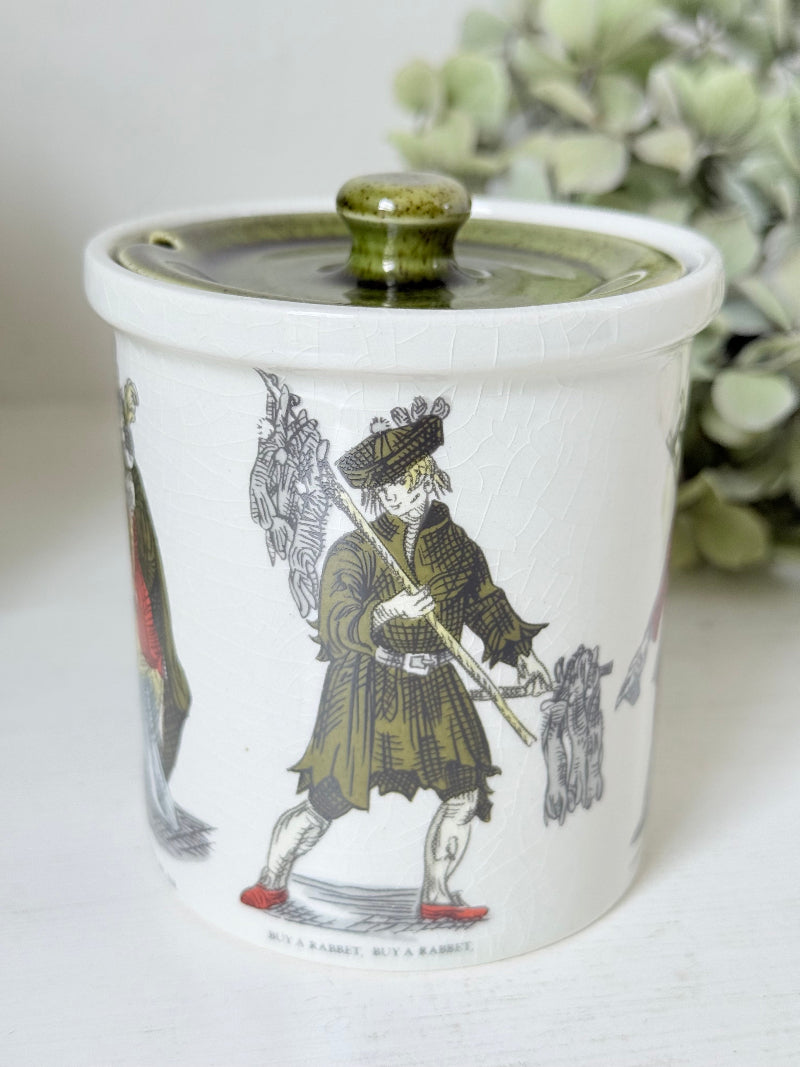 vintage Holkham pottery condiment pot with green lid and illustrated figures photographed on white surface