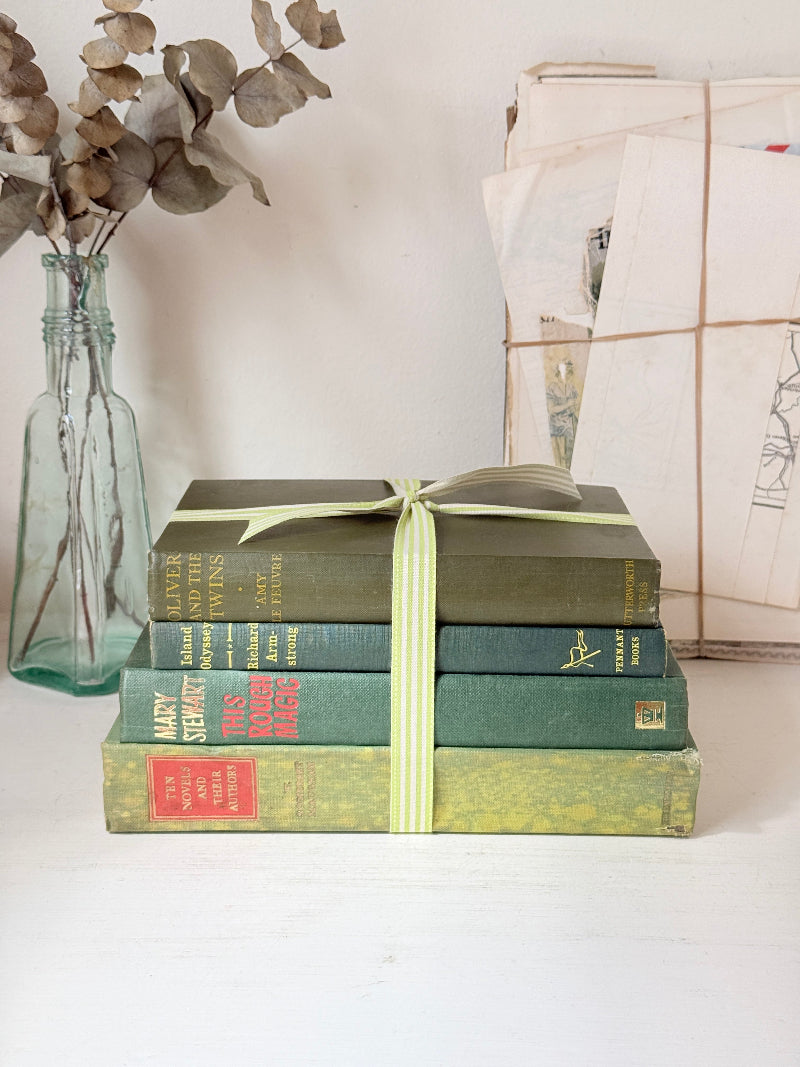 Bundle of vintage sage and olive green cloth books with red spine detail tied with a pale ribbon for styling