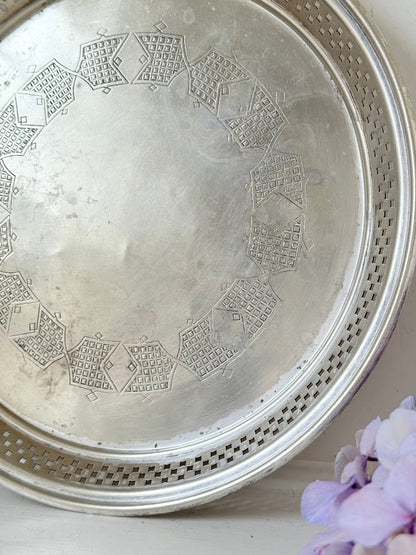 Vintage round silver plate tray with brass rim, pierced edge and etched central motif, photographed on white surface