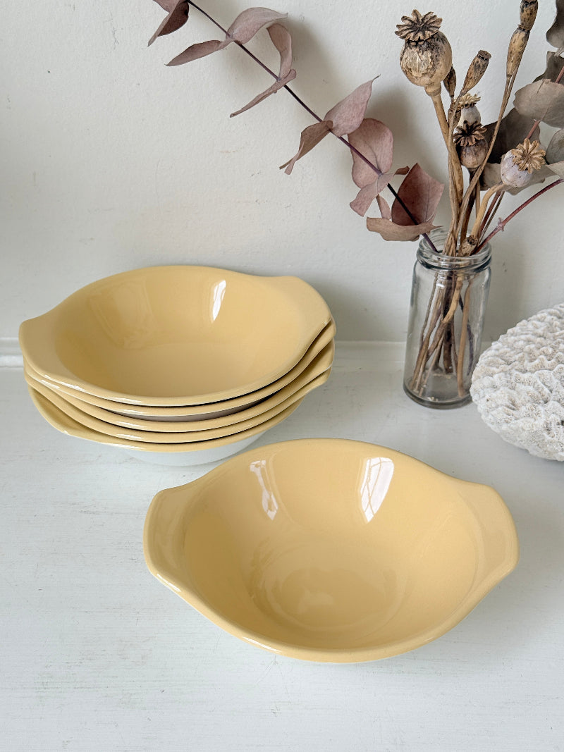Set of six vintage Poole Pottery lemon bowls in butter yellow glaze photographed on a white surface