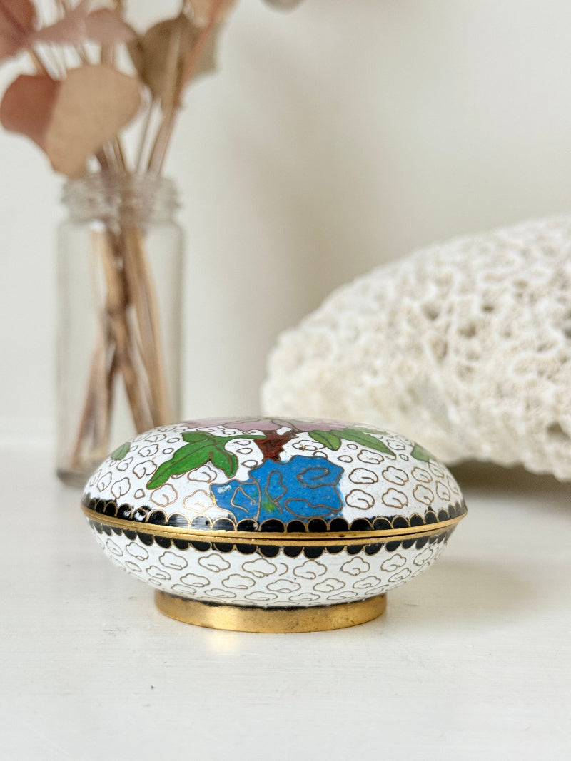 Vintage brass and enamel cloisonne trinket box with floral lid and turquoise interior photographed on a white surface