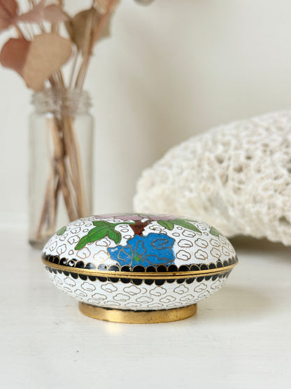 Vintage brass and enamel cloisonne trinket box with floral lid and turquoise interior photographed on a white surface