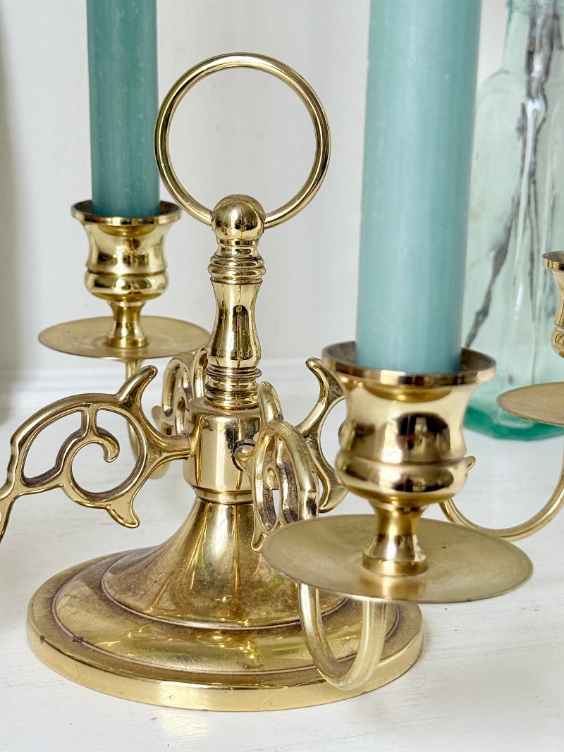 Brass five light candelabra with scrolled arms and a central ring handle on a domed base, photographed on a white surface