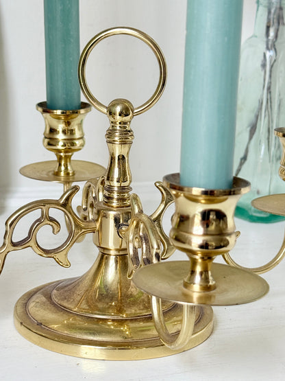 Brass five light candelabra with scrolled arms and a central ring handle on a domed base, photographed on a white surface