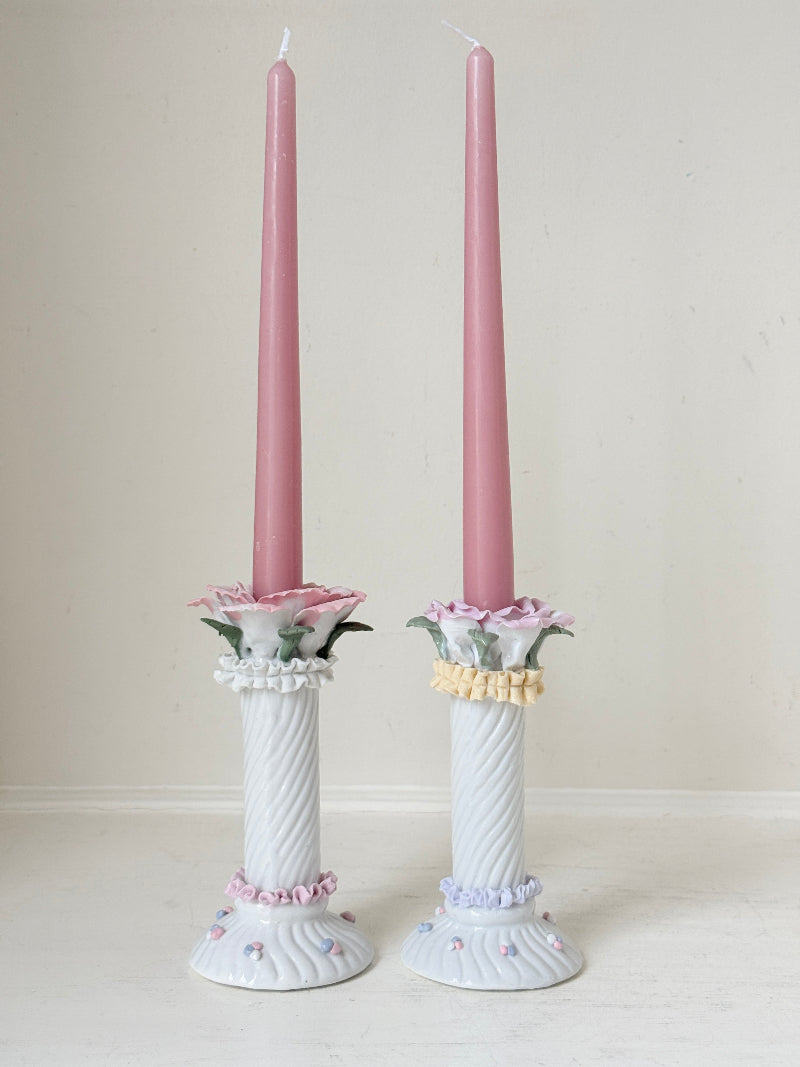Pair of vintage floral ceramic candlesticks with rose candle cups and pink taper candles styled on a white surface