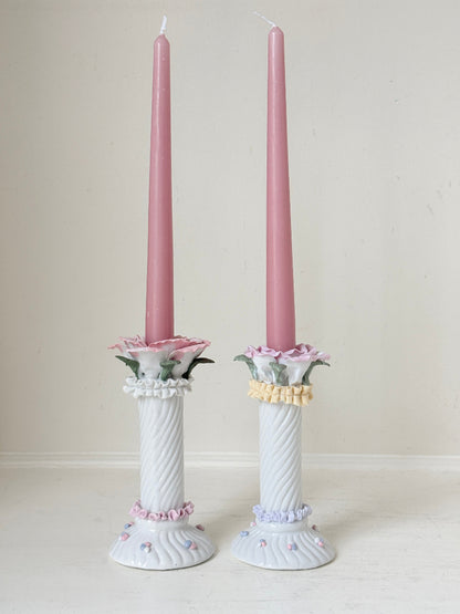Pair of vintage floral ceramic candlesticks with rose candle cups and pink taper candles styled on a white surface