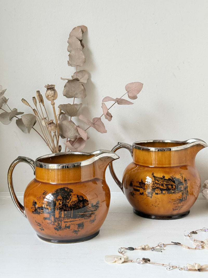 Pair of vintage Ridgways Coaching Days and Coaching Ways treacle jugs in amber brown glaze photographed on a white surface