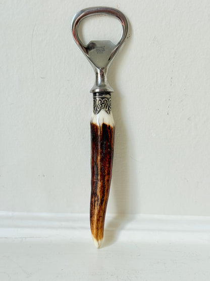 vintage antler handle bottle opener with stainless steel top photographed on white surface