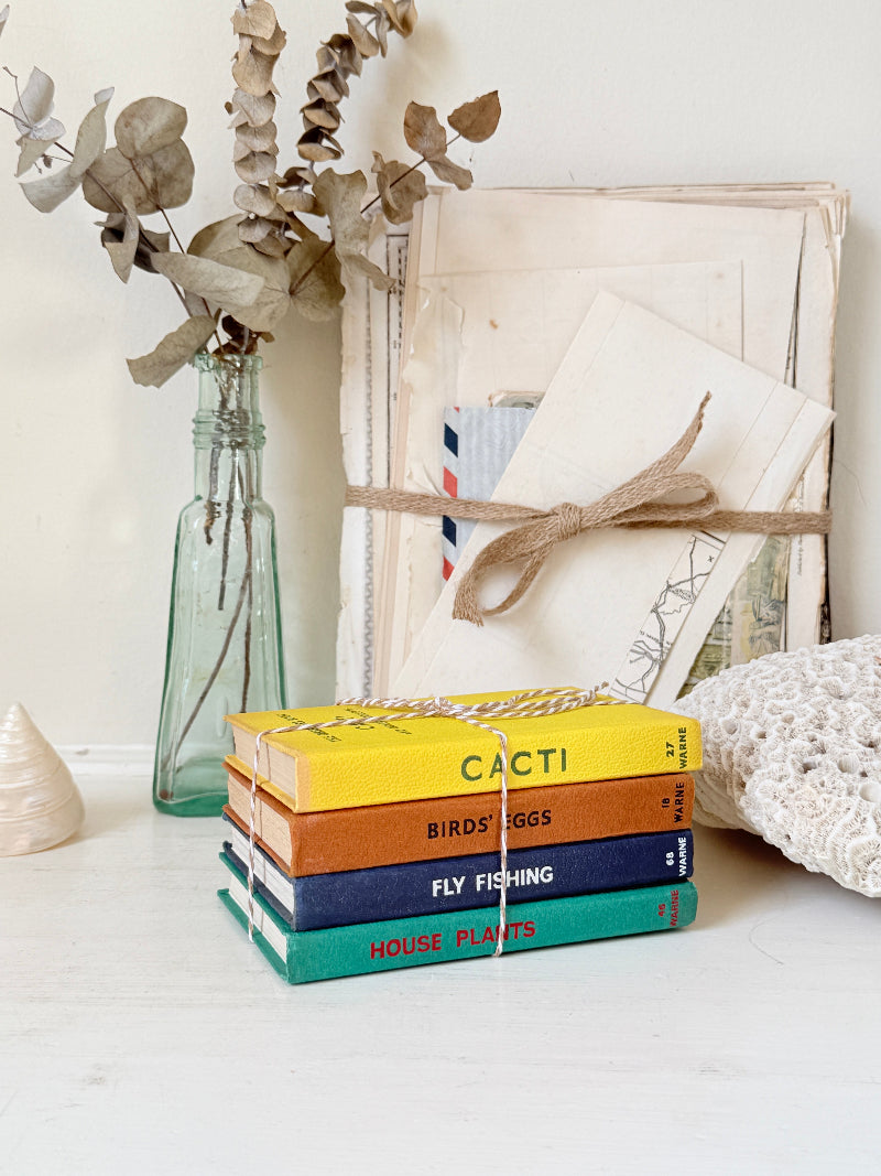 A stack of four hardcover books with colorful spines labeled &
