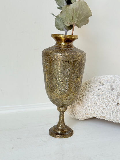 Indian Benares brass chalice vase with figural panels and pedestal base, photographed on a white surface