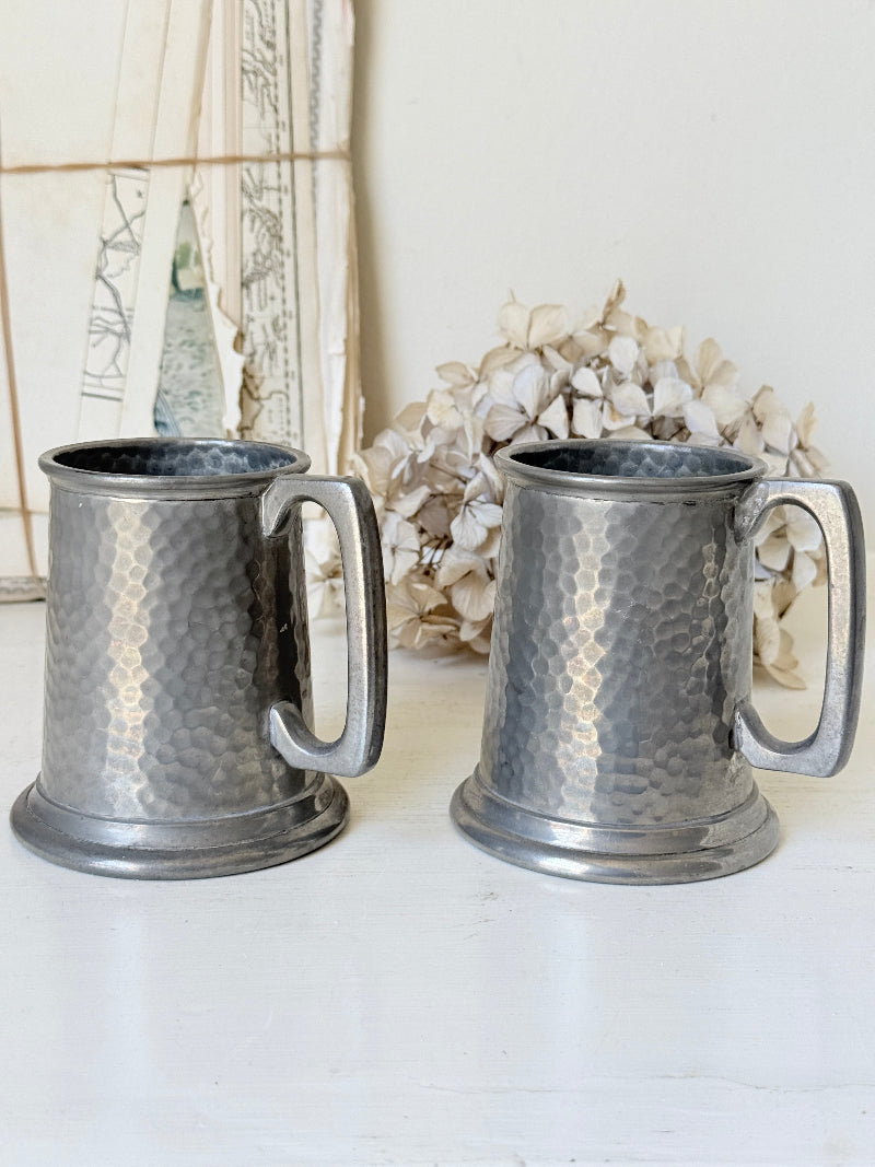 Pair of hammered English pewter tankards by E H Parkin of Sheffield, photographed on a white surface