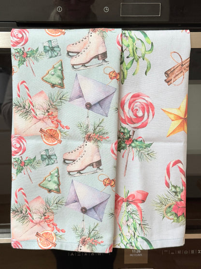 Pair of pastel blue festive tea towels with candy cane and ribbon print, folded, photographed on a kitchen worktop