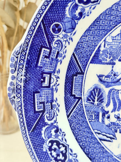 Blue Willow serving plate with cobalt blue transfer pattern shown on a white surface.