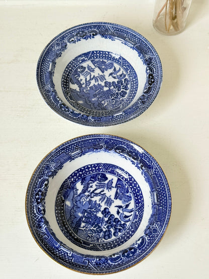 Pair of vintage blue and white Blue Willow snack bowls with patterned border photographed on a white surface