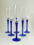 Set of six vintage French champagne flutes with tall clear bowls and cobalt blue twisted stems, photographed on white surface.