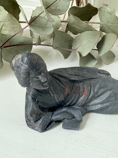 antique japanese bronze reclining lady with impressed marks to base photographed on white surface with foliage background