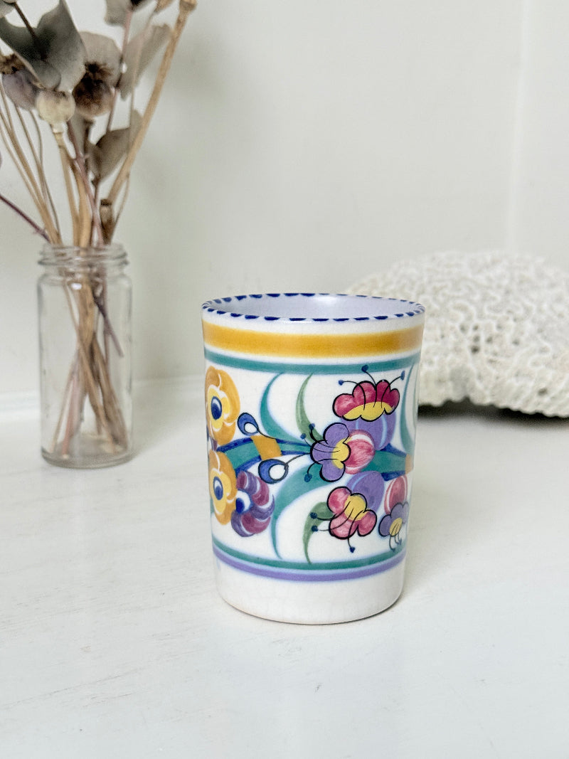Vintage Poole Pottery pen pot with colourful floral design photographed on a white surface