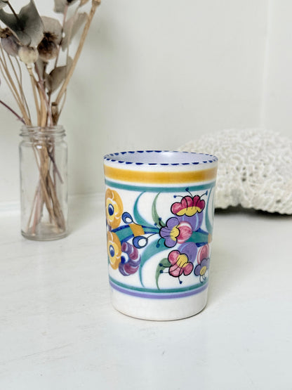 Vintage Poole Pottery pen pot with colourful floral design photographed on a white surface
