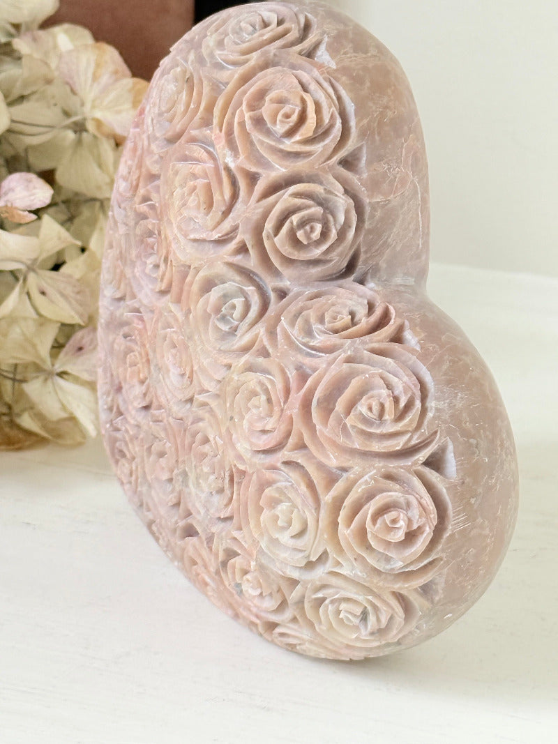 vintage pink stone heart with engraved roses and flat base on white surface