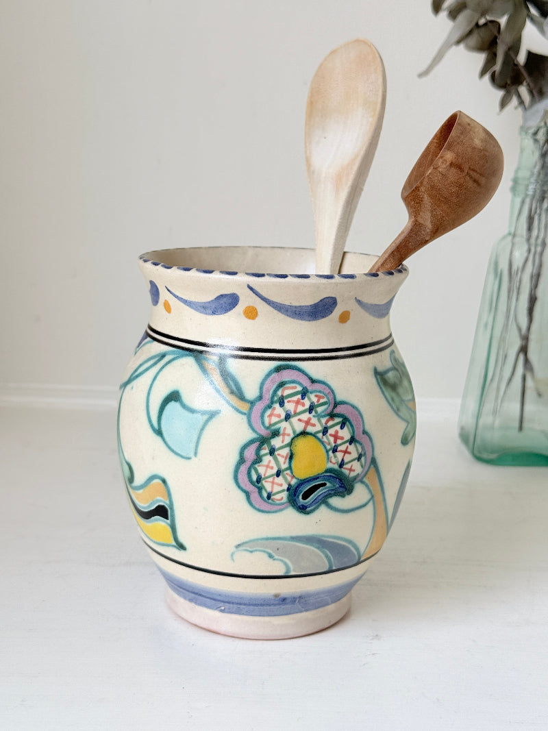 Hand painted floral pottery vase in blue and green on cream, photographed on a white surface