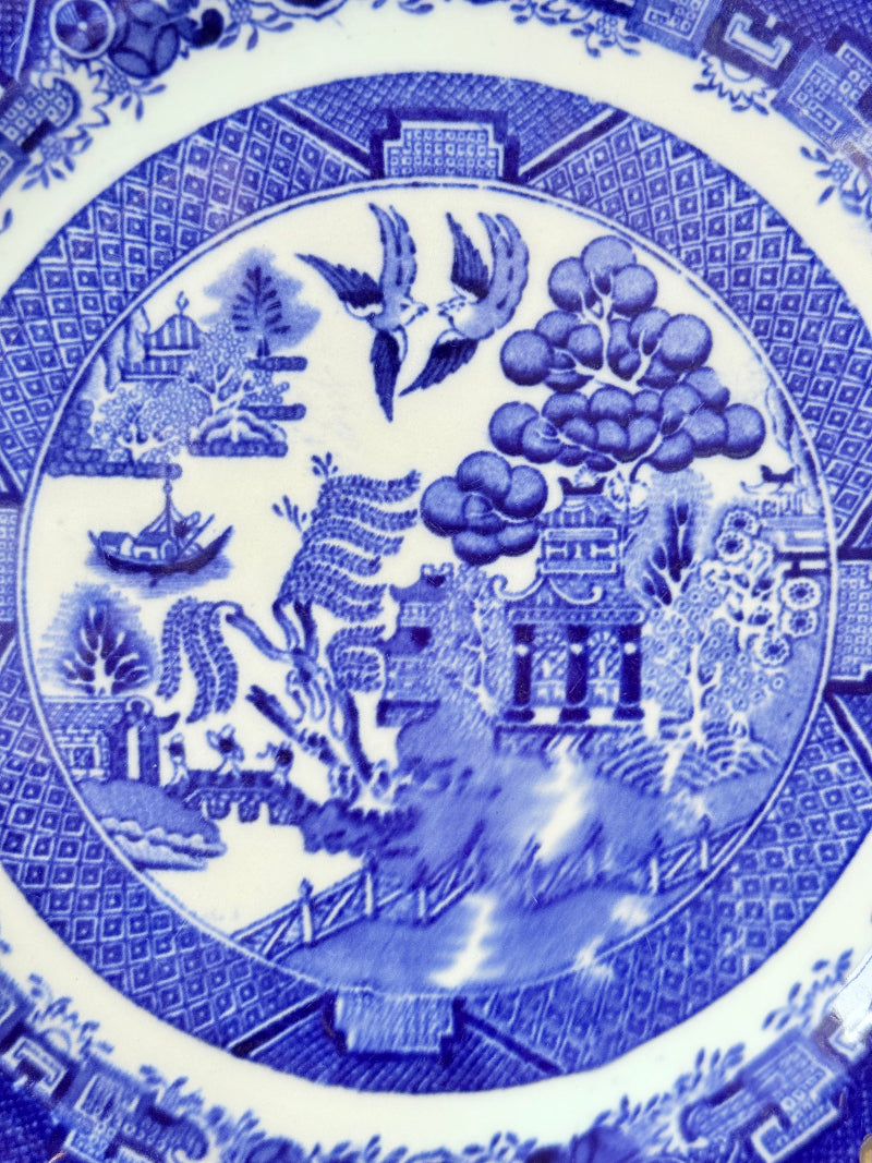 Blue Willow serving plate with scroll handled relief shown on a white surface.