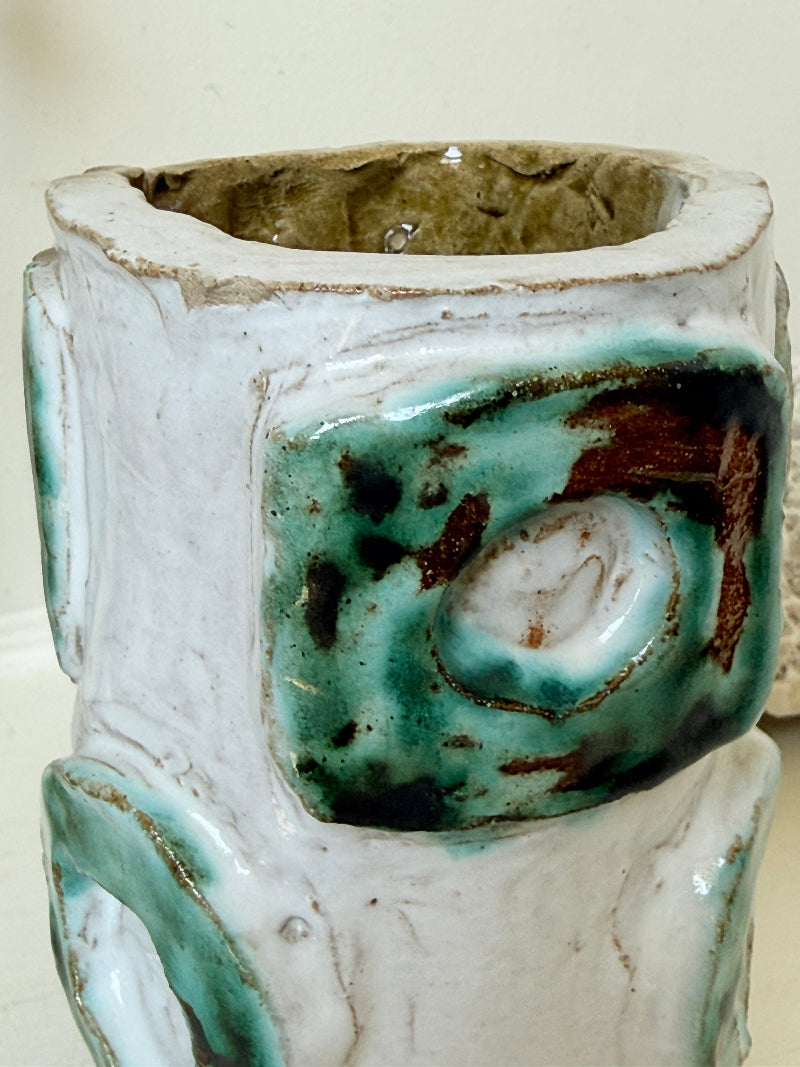 Vintage studio pottery vase in white, ochre and turquoise with abstract applied decoration, photographed on a white surface