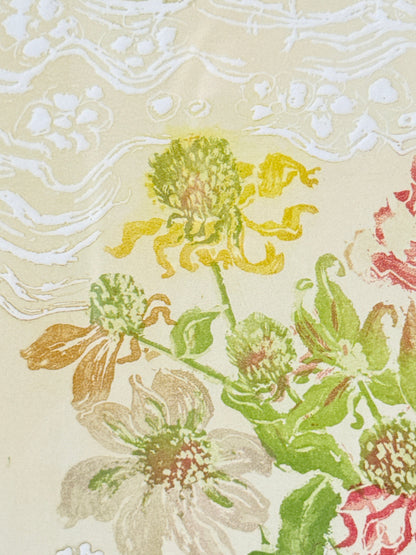 A close-up of a floral fabric pattern featuring yellow, green, and pink flowers on a warm beige background with a white wavy pattern.
