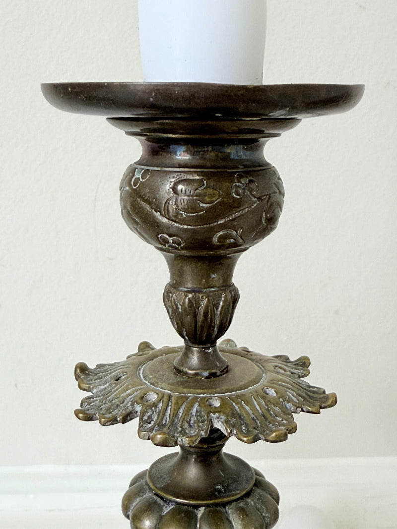 pair of antique brass candlesticks with turned detailing on white surface