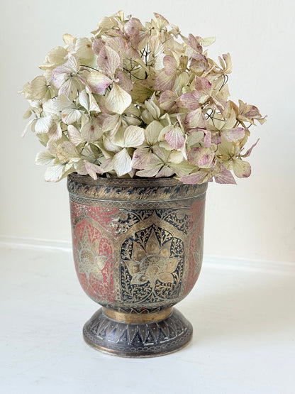 vintage indian metal lassi cup with red and white enamel motifs, styled with dried hydrangeas on a white surface