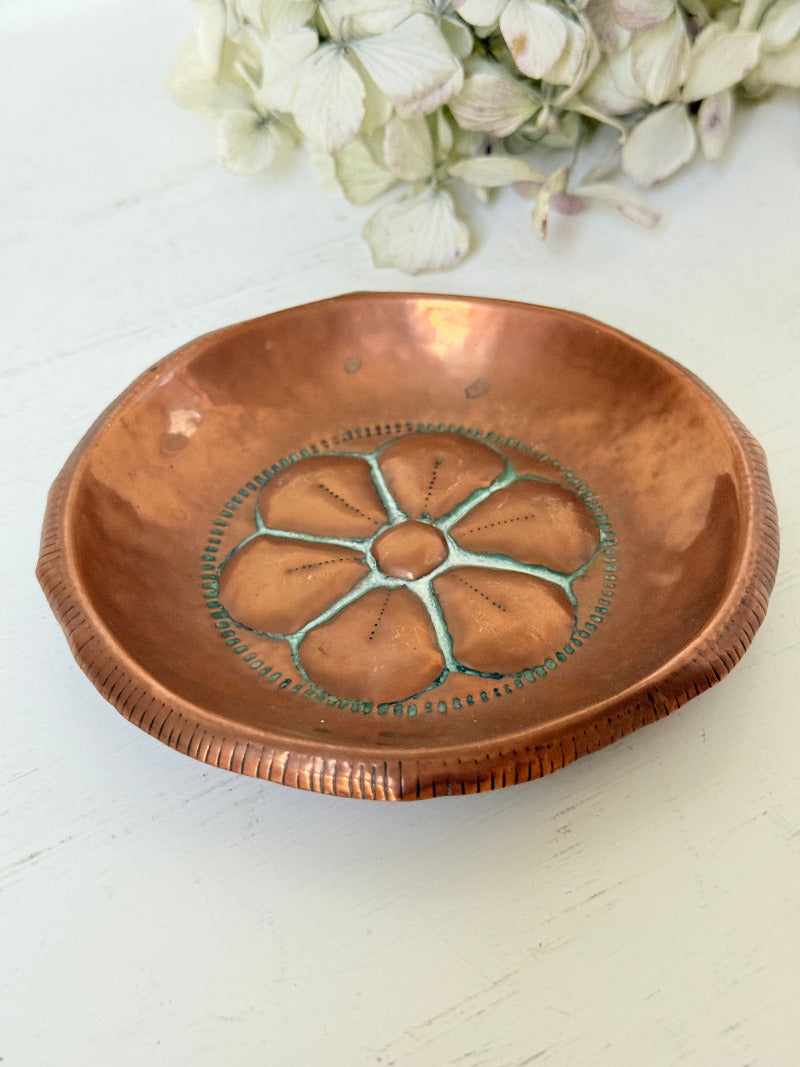 small vintage copper dish with cut-out floral centre photographed on white surface
