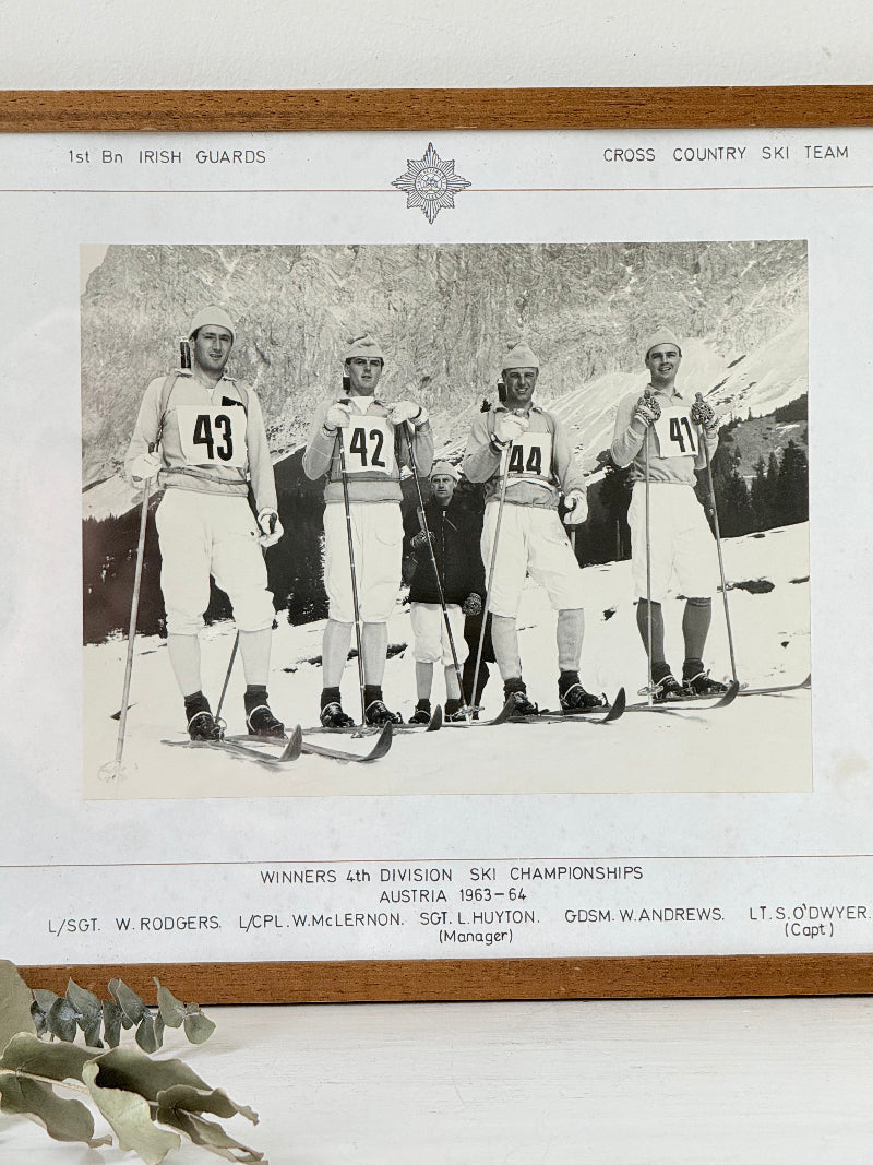 Vintage black and white framed photograph of the 1st Battalion Irish Guards Ski Team, 1963–64, posed in full ski gear against the Austrian Alps.