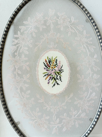 Vintage oval metal tray with pierced gallery sides, twin handles, and floral centre, photographed on white surface.