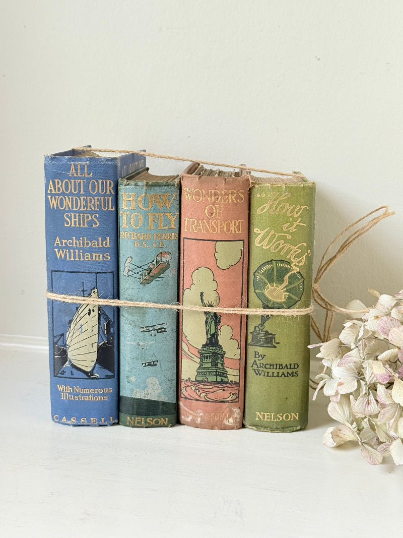 Vintage decorative book bundle in green, blue, and coral with printed lettering, tied with twine, photographed on a white surface