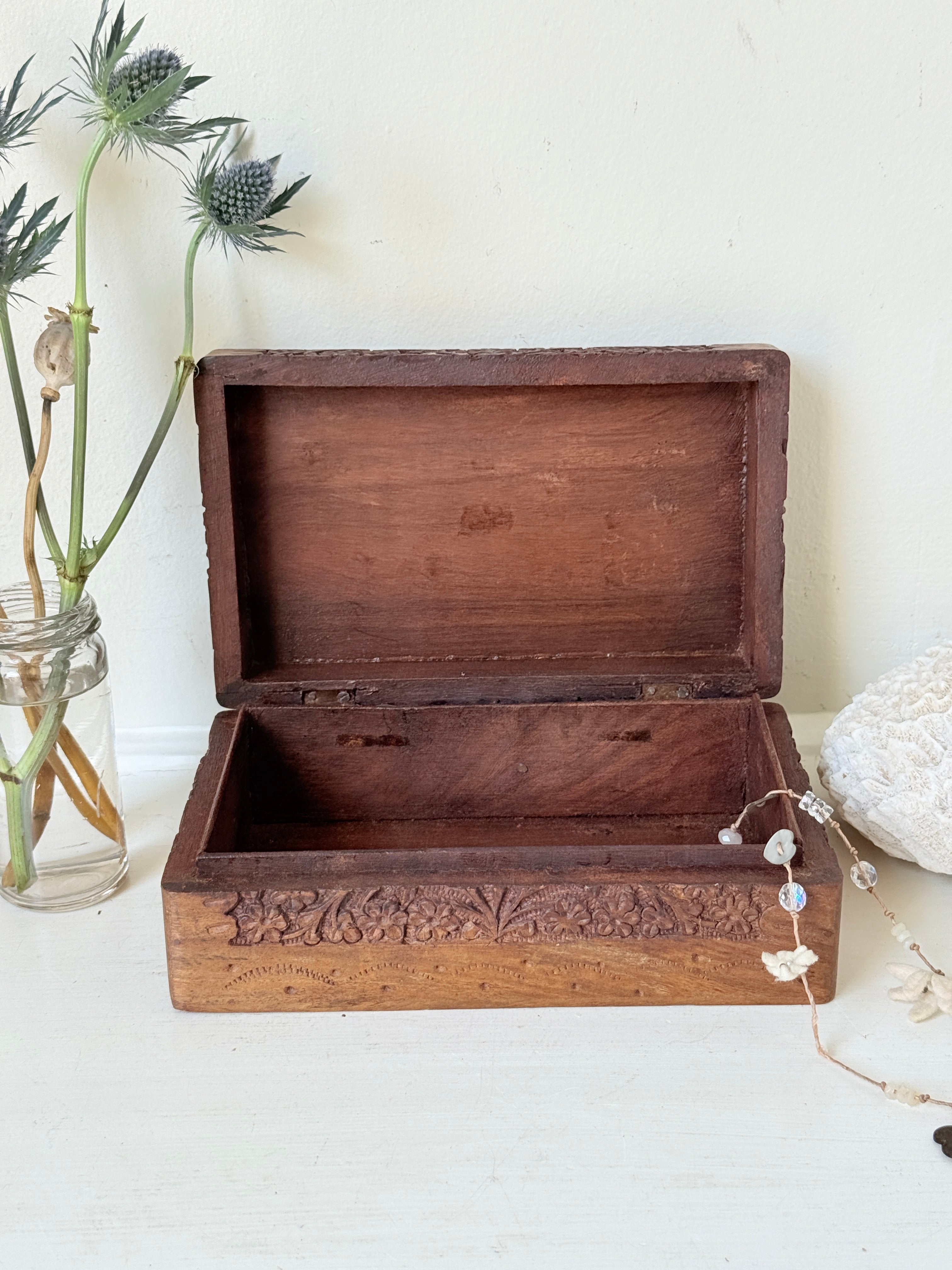 Vintage floral carved wooden jewellery box with detailed hand carved decoration, photographed on a white surface