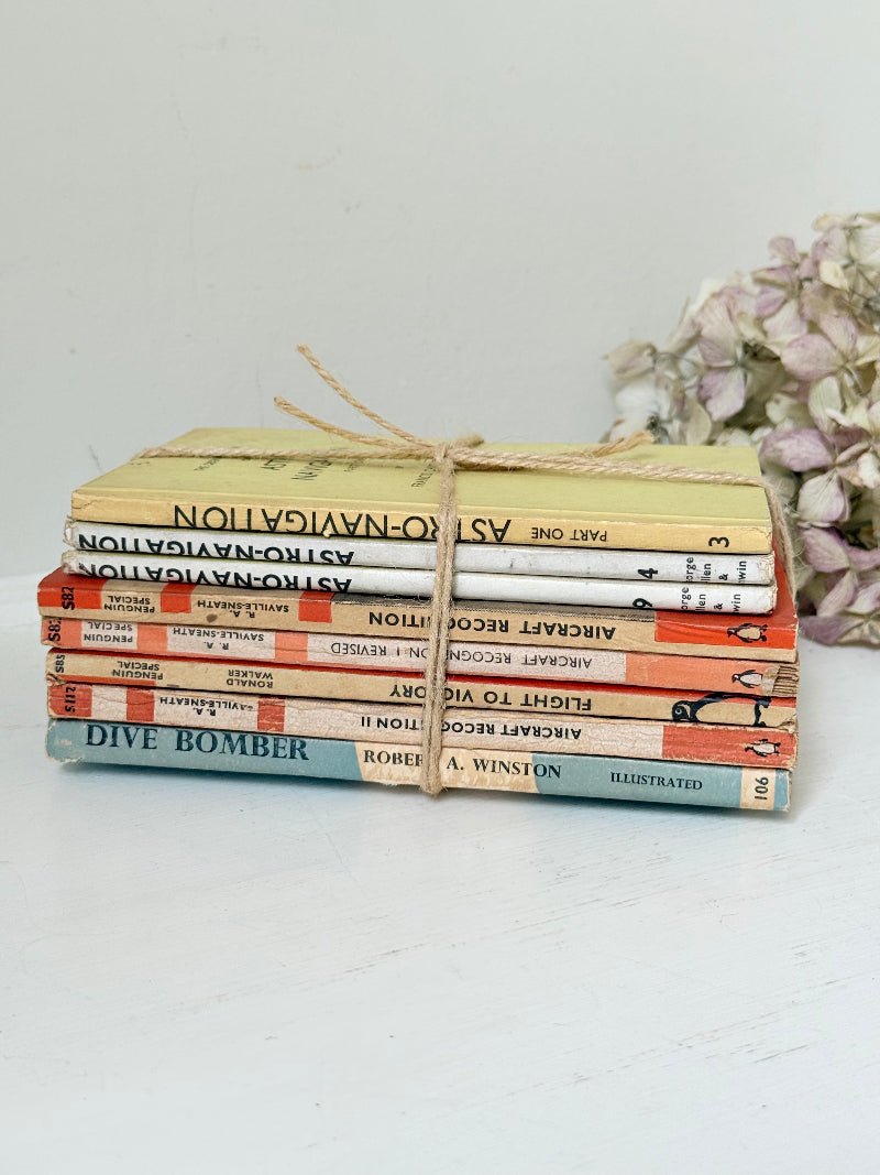 Bundle of vintage Penguin paperback books in orange and cream tones tied with twine, photographed on a white surface
